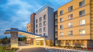 Un hotel de varios pisos con fachada moderna, entrada cubierta y estacionamiento con acceso para personas con discapacidad.