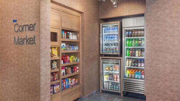 Una tienda de barrio con estantes llenos de aperitivos, bebidas y productos envasados.