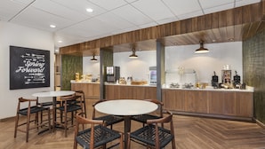 Un café moderno con detalles de madera, una pared de azulejos blancos y una pizarra de menú.
