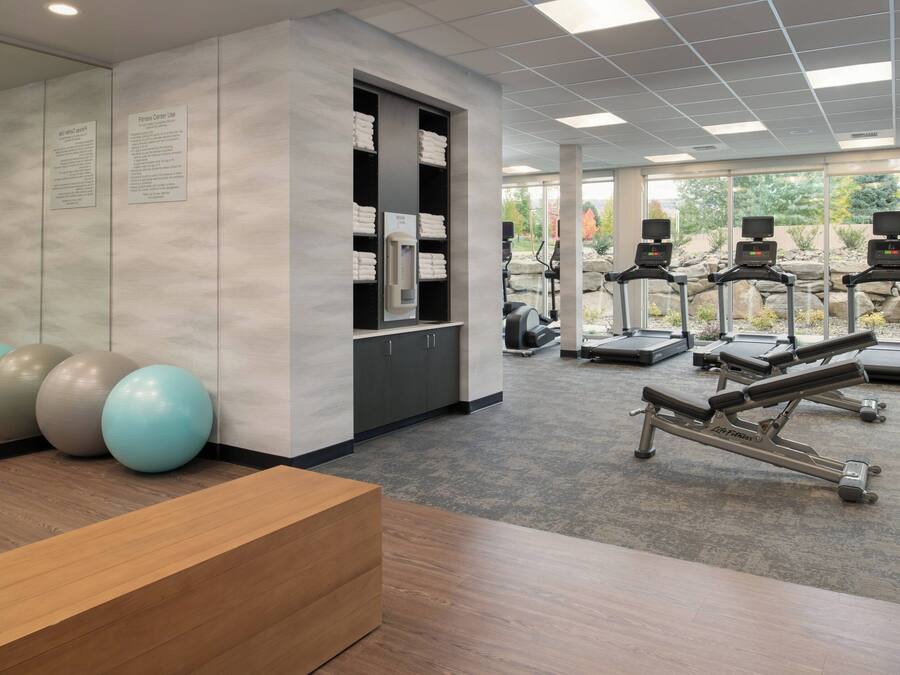Uma academia com equipamentos de ginástica, uma mesa de recepção e vista para o exterior.