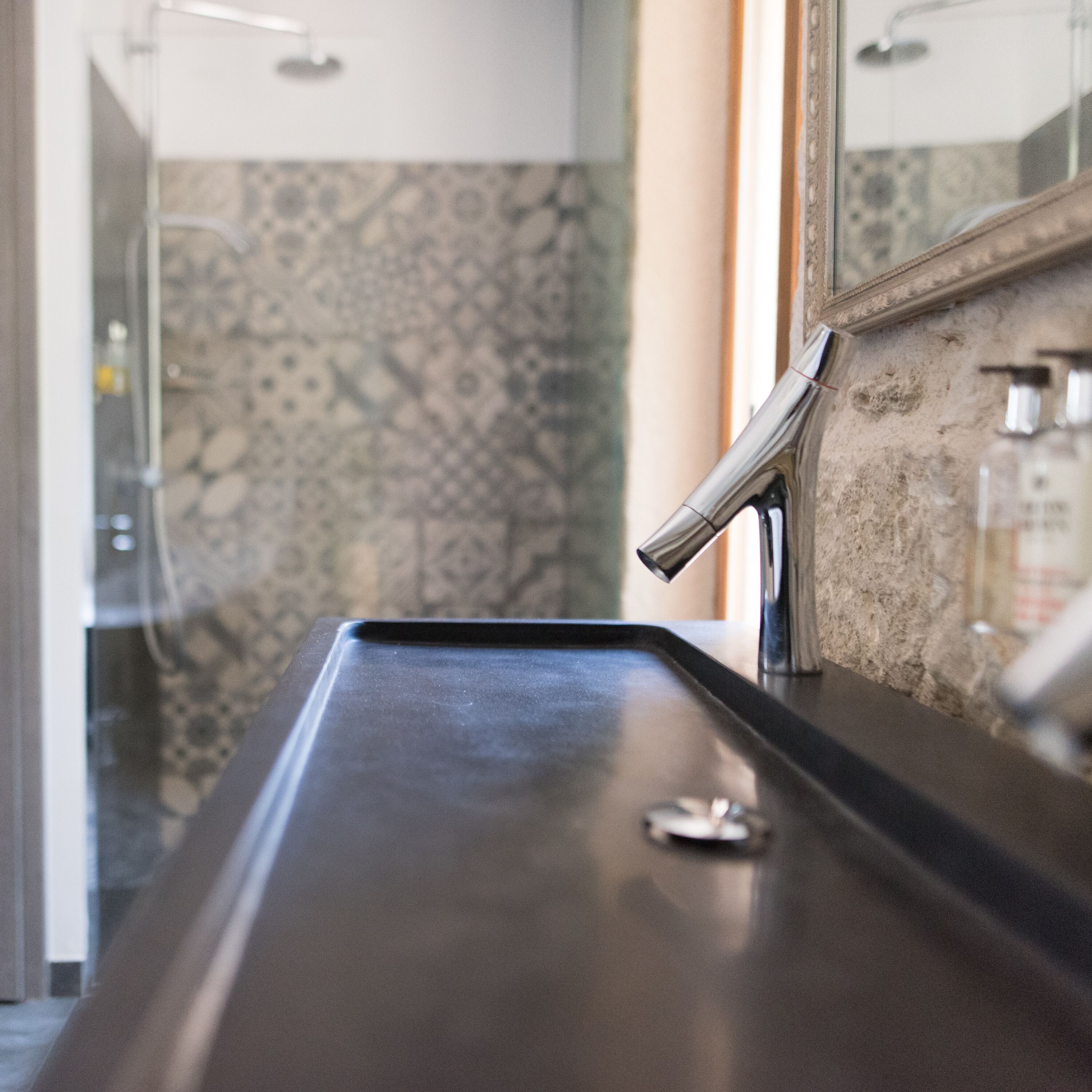 A bathroom with a black sink, a mirror, and a shower area.