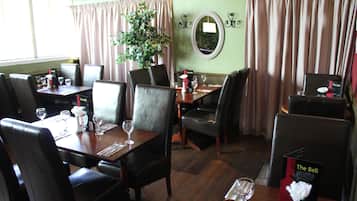 Un restaurante con una mesa de madera preparada para comer, rodeada de sillas.