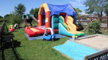 A play area with inflatable slides and a small blue car.
