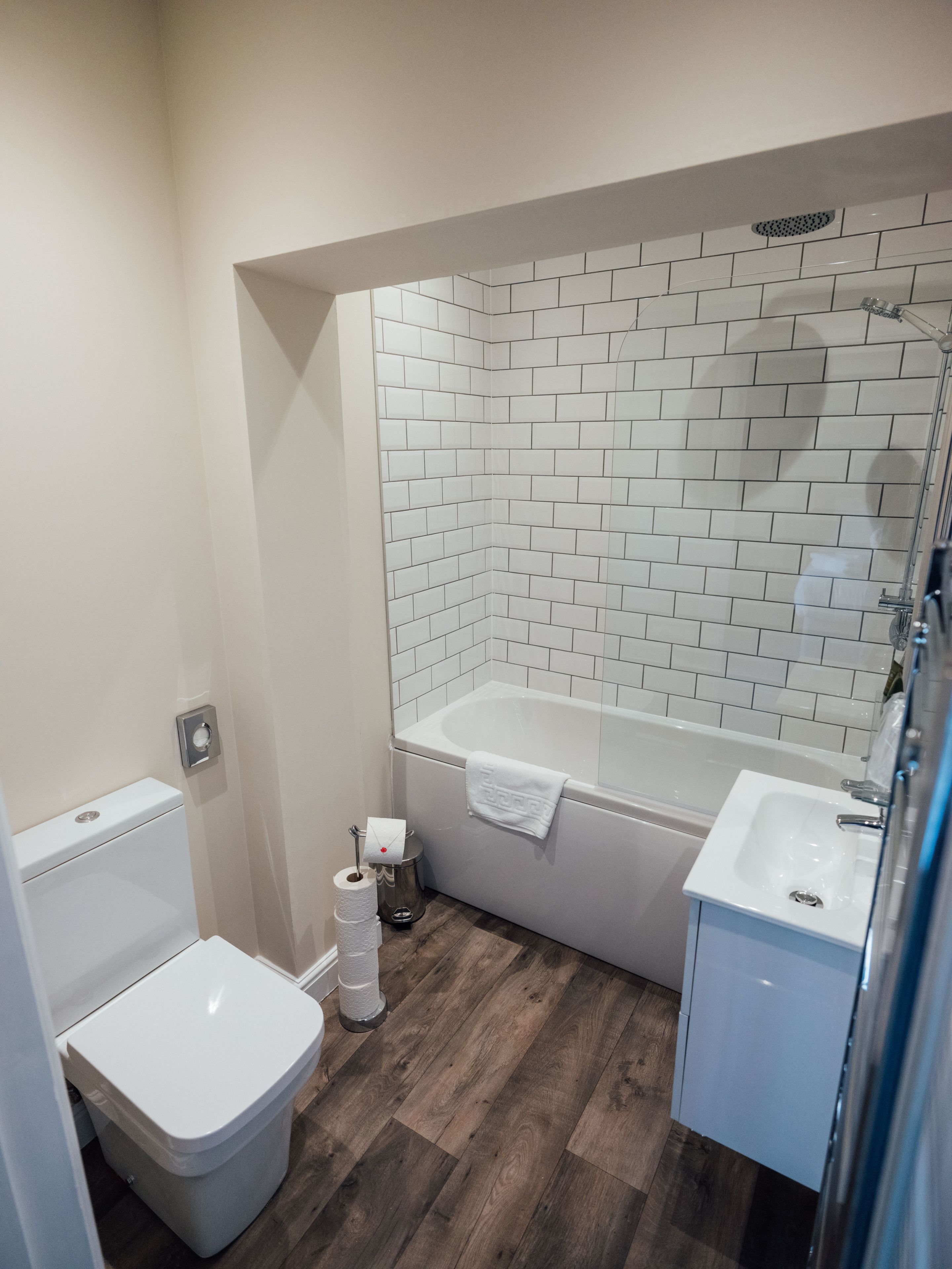 Ein Badezimmer mit Toilette, Waschbecken und Badewanne mit Duschkopf.
