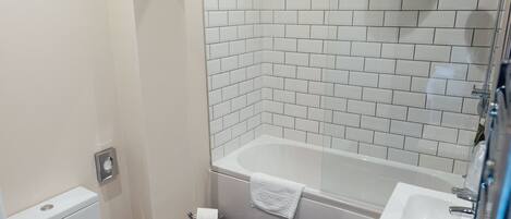 A bathroom with a white toilet, a white sink, and a bathtub with a showerhead.