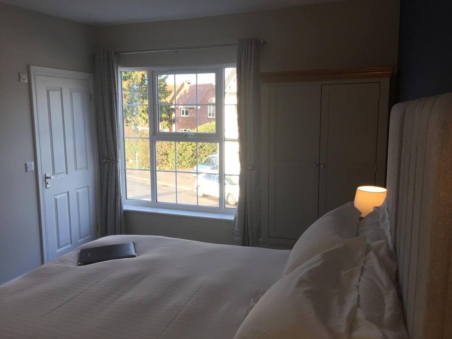 Ein Schlafzimmer mit einem Bett, einem fensterbepflanzten Fenster, einem Kleiderschrank und einer Lampe auf dem Nachttisch.