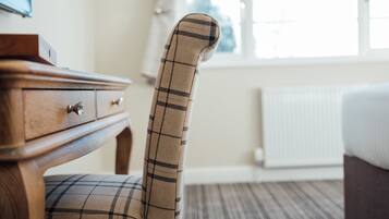 A plaid-patterned chair in a hotel room with a wooden dresser and a radiator.