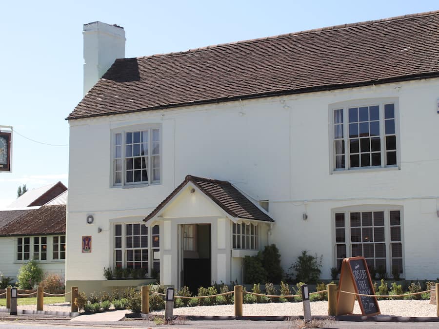 A white building with a tiled roof and a small porch.