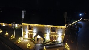 Een gebouw met veel ramen en een kleine ingang, omringd door sneeuw en verlicht met lichtslingers.