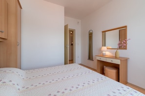 A bedroom with a bed, a dresser, a mirror, and a nightstand.