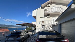 A building with a garage, a covered parking area, and a view of the sea. - Mandic Apartment - Seaside Views, Beach Nearby (Mastrinka)