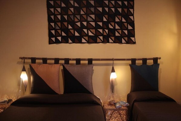 A hotel room with two beds, a geometric wall hanging, and bedside lamps. - Dimora dei Giganti - a typical neapolitan terrace (Napoli)
