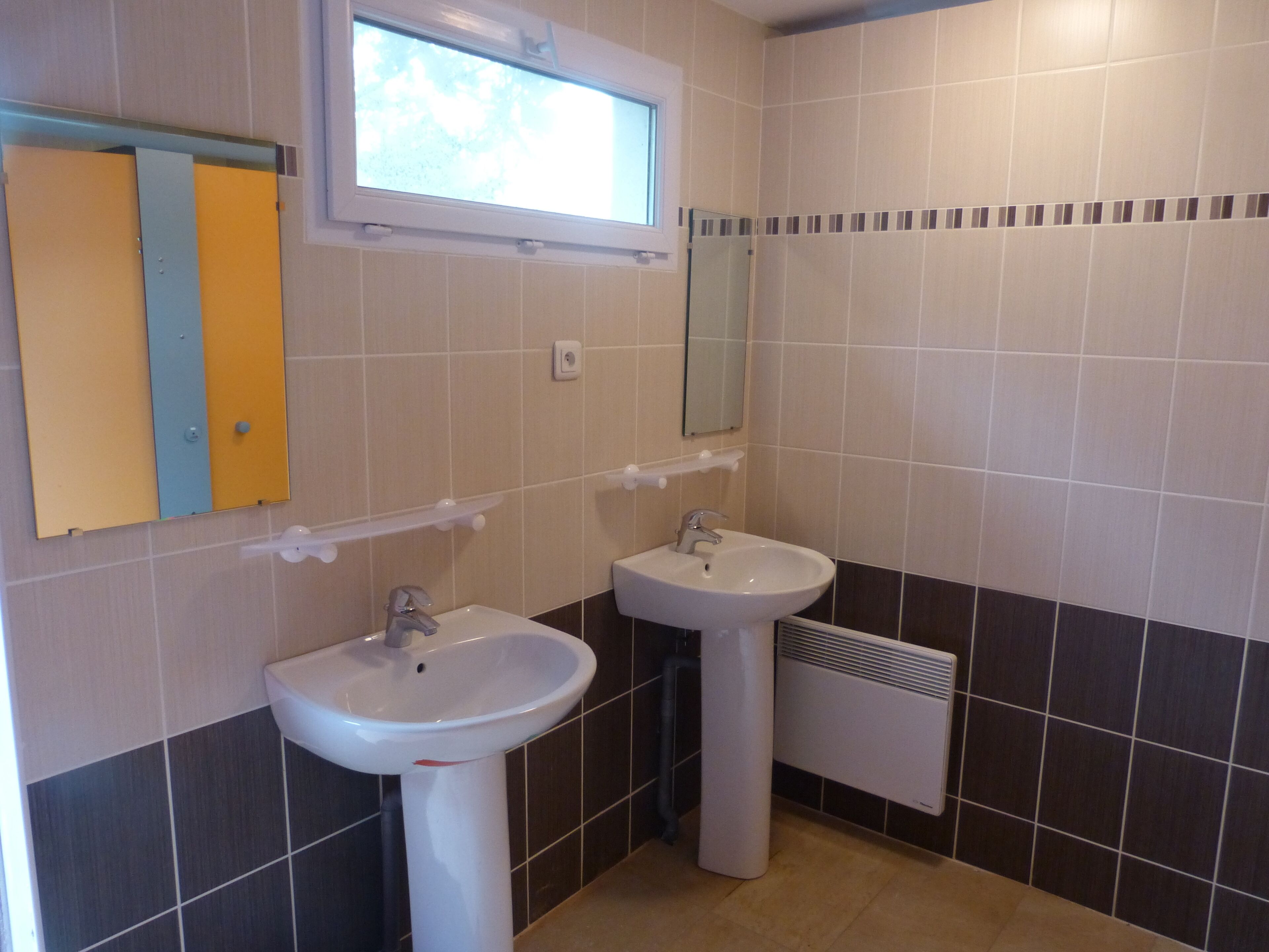 Ein Badezimmer mit zwei Waschbecken, einem Fenster und einem Spiegel.