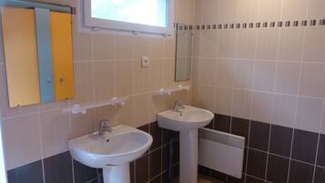 Ein Badezimmer mit zwei Waschbecken, einem Fenster und einem Spiegel.
