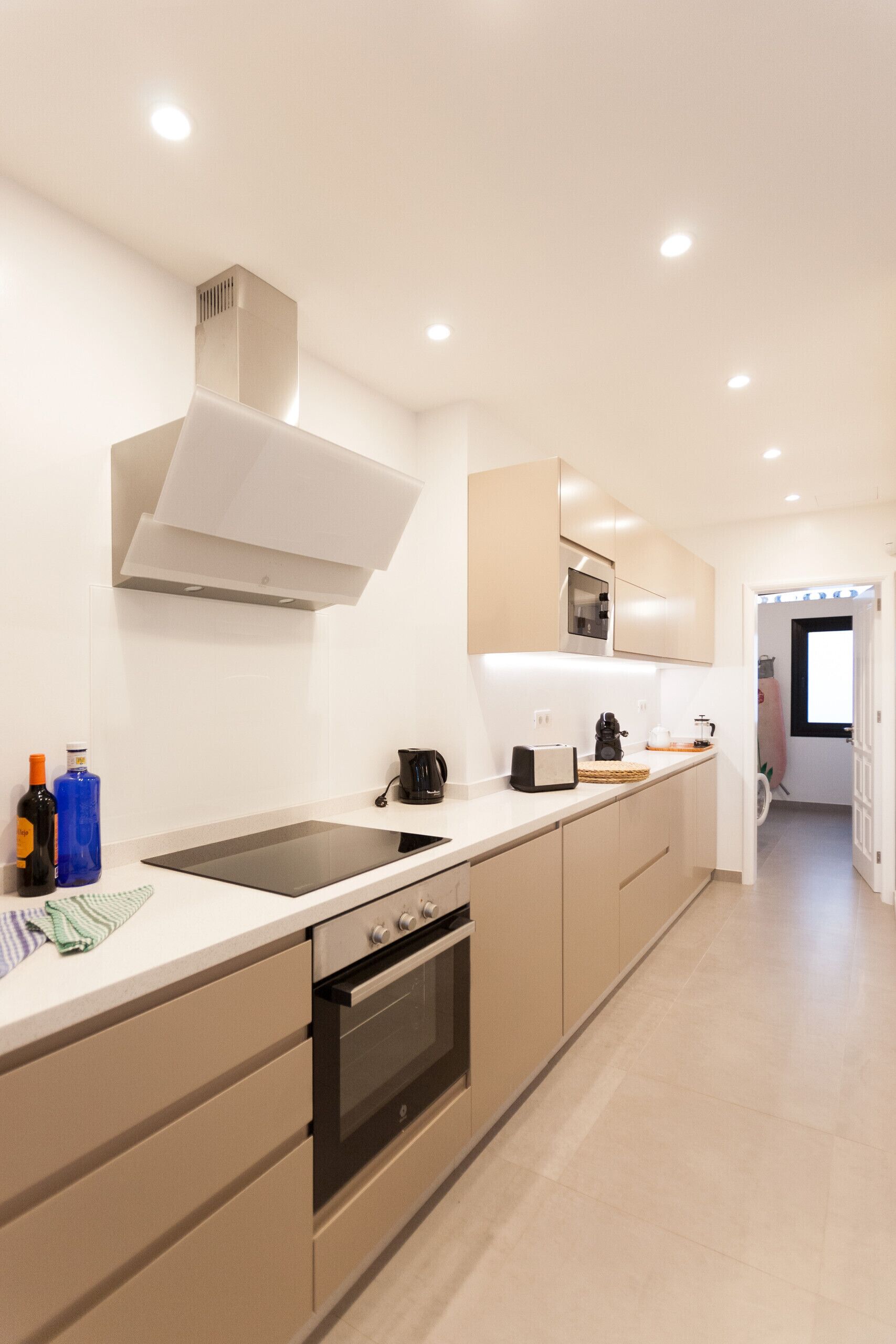 A modern kitchen with a central island, built-in oven, and stainless steel appliances.
