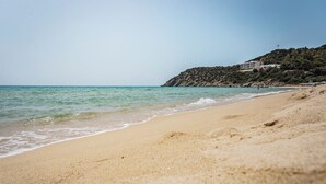Una playa con orilla arenosa y un edificio en una colina al fondo.