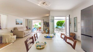 Un amplio espacio de estar con una mesa de comedor, sillas, un sofá y una zona de cocina con un refrigerador.