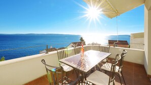 Un balcon avec une table et des chaises, donnant sur une étendue d’eau.
