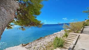 Un sentier côtier avec des marches descendant vers la mer, bordé d’un terrain rocheux et d’une végétation clairsemée.