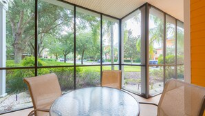 A room with a glass table and two chairs, large windows offering a view of a campus with trees and buildings. - Bahama Bay, Florida 2 Br large condominium (Davenport)