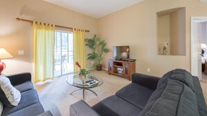 A living room with a sofa, a glass coffee table, a television on a wooden stand, and a potted plant. - Bahama Bay, Florida 2 Br large condominium (Davenport)