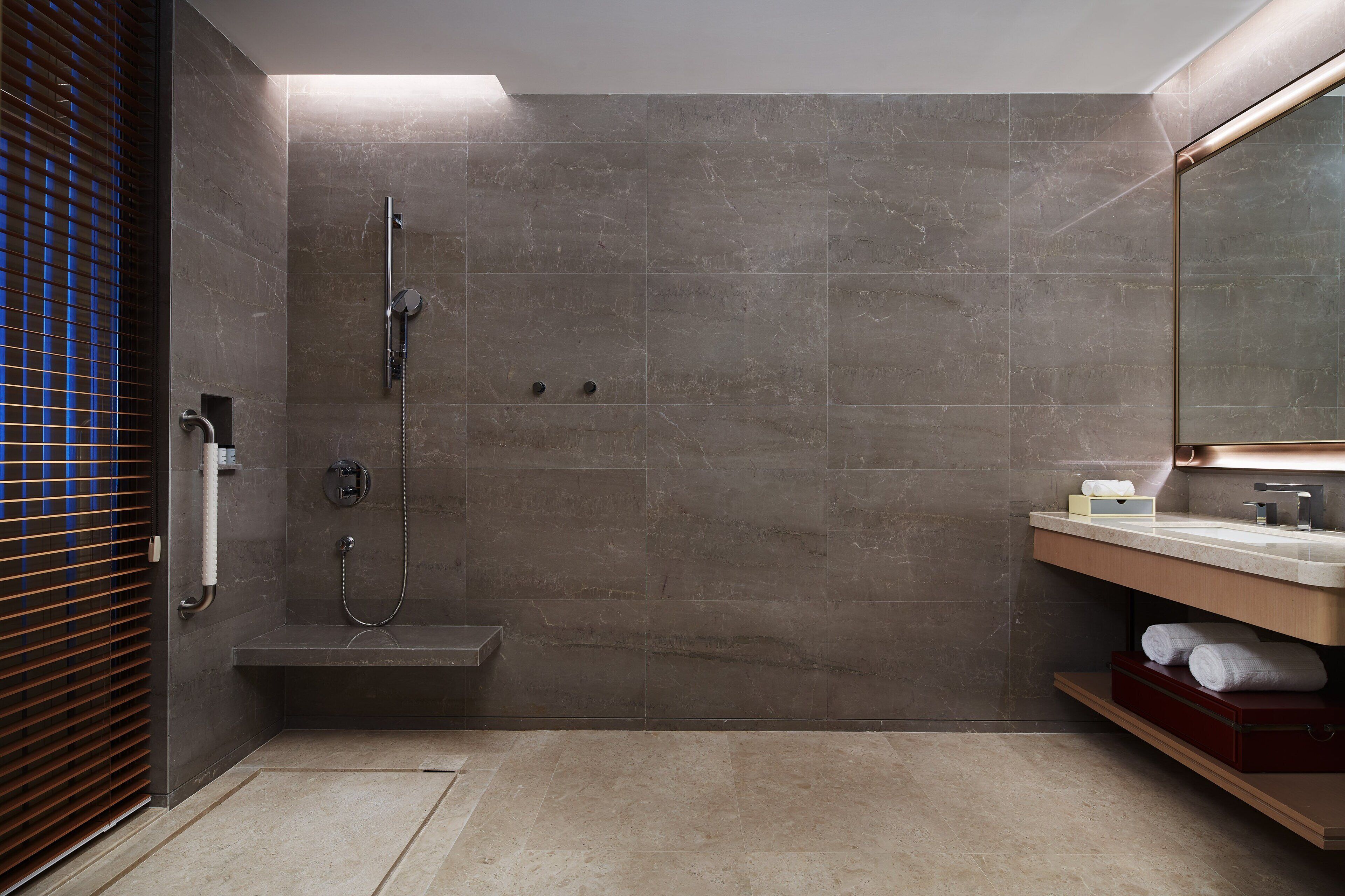 A modern bathroom with a walk-in shower, a vanity with a mirror, and a towel rack.
