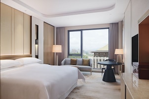 Una habitación de hotel con una cama grande, un sofá, una mesita y un televisor.
