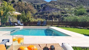 A swimming pool with lounge chairs and a drink on the deck.