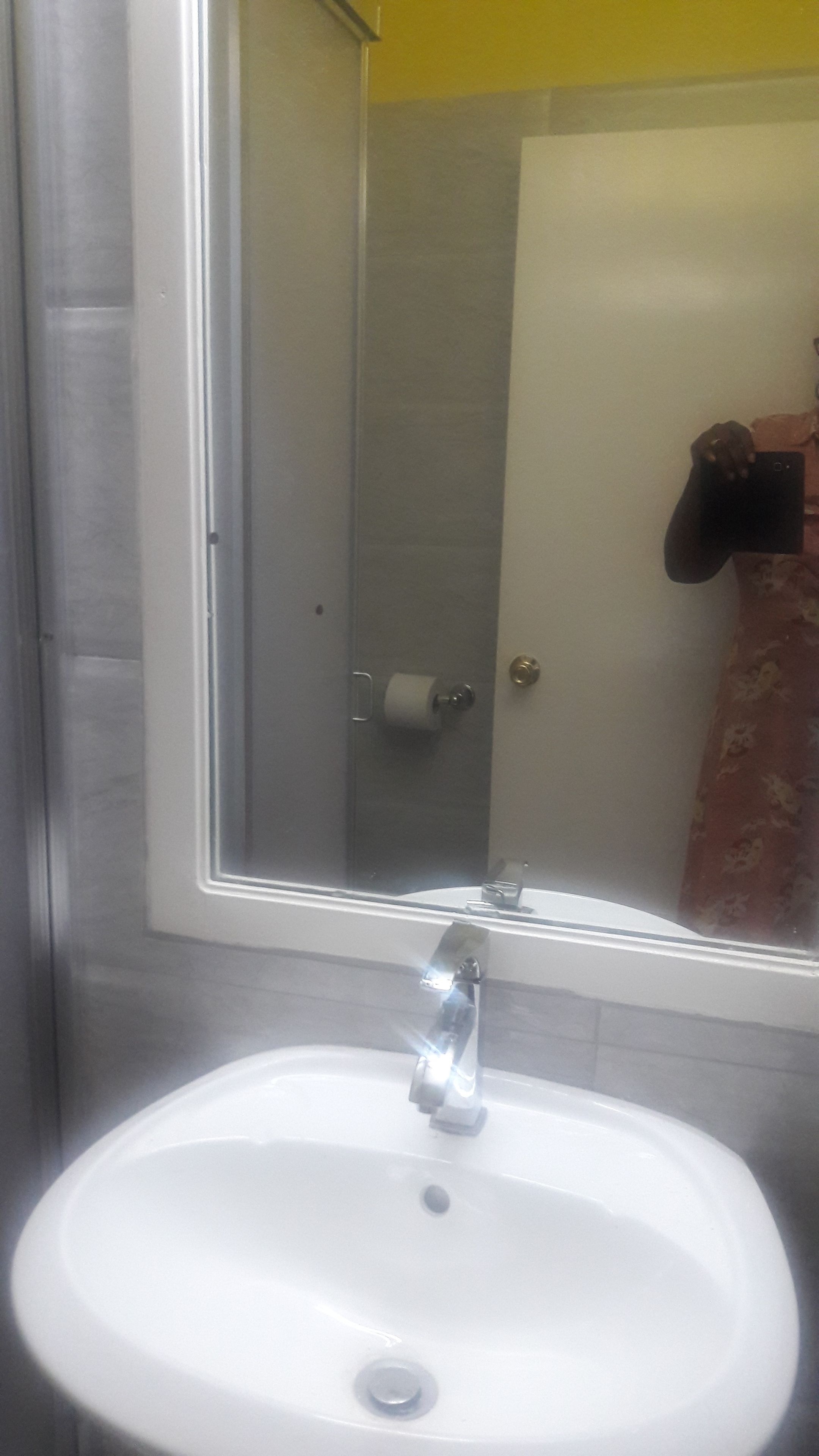 Un baño con lavamanos blanco, un espejo y zona de ducha.