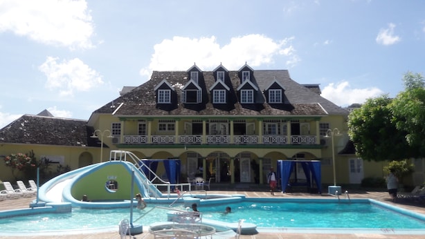 A large building with a swimming pool and a slide. - Sunny View At Sandcastle (Ocho Rios)