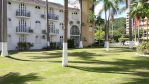 A building with multiple balconies, air conditioning units, and a well-maintained lawn with palm trees. - Sunny View At Sandcastle (Ocho Rios)