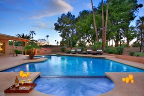 A swimming pool with lounge chairs and candles, surrounded by palm trees and a building. - Casa De Encanto (Scottsdale)