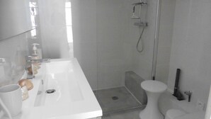 A modern bathroom with a white sink, mirror, and shower.