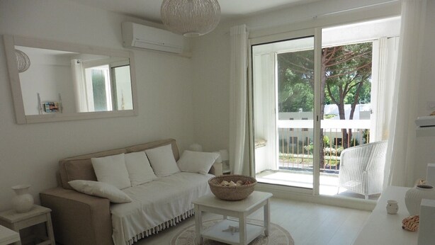 A minimalist living room with a sofa, a round coffee table, and a wicker chair.