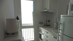 A modern kitchen with white cabinets, a stainless steel range hood, a built-in oven, and a refrigerator.