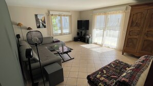 Un salon avec un canapé, une table basse, un téléviseur et un meuble.