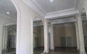 Een ruime kamer met hoge plafonds, grote ramen en een spiegelwand.