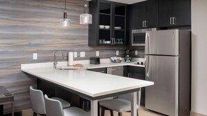 A modern kitchen with a large island, stainless steel appliances, and dark cabinetry.