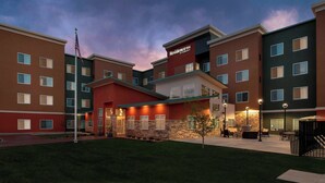 A multi-story hotel with a red and brown facade, multiple windows, and a well-lit entrance.