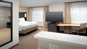A hotel room with a bed, a desk, a TV, and a chair.