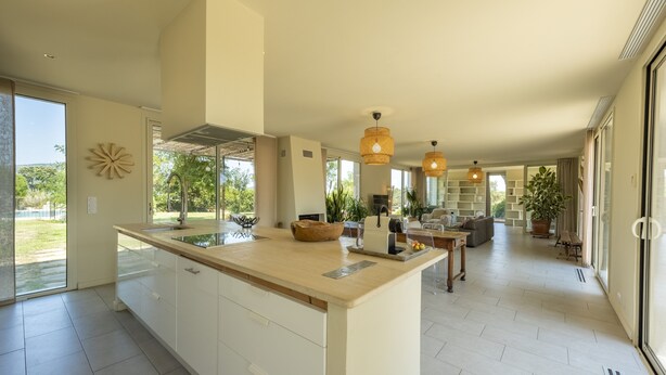 A spacious kitchen with a large island, pendant lighting, and a view of the outdoors.