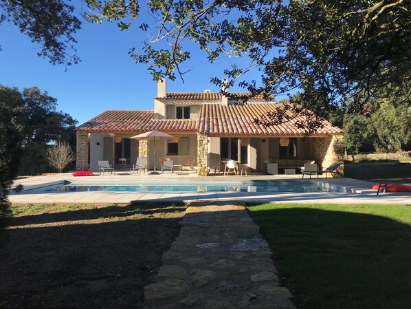 A house with a swimming pool, stone exterior, and outdoor seating area.