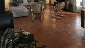 En stue med sofa, to gyngestole, pejs og hængende pendellamper.