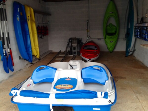 Un espace de stockage pour bateaux, avec des kayaks et un bateau à moteur.