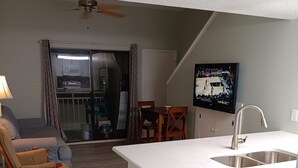 A modern kitchen with white cabinetry, a built-in sink, and a dining area with a table and chairs. - Affordable Renovated Beachside At Sugar Beach Condos in Orange Beach, AL (Orange Beach)