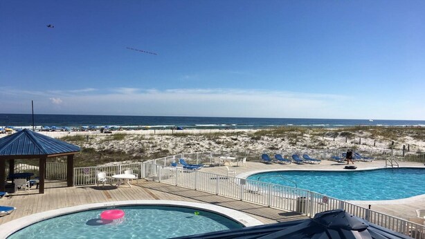 A beachside pool area with lounge chairs and a gazebo, overlooking the ocean. - Affordable Renovated Beachside At Sugar Beach Condos in Orange Beach, AL (Orange Beach)