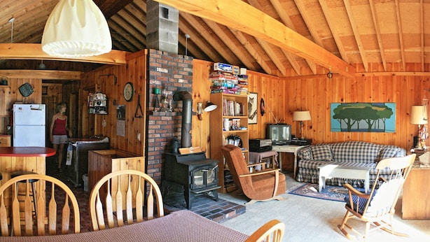 Un intérieur de chalet chaleureux comprenant un coin repas, un salon avec un canapé et une télévision, et une cuisine équipée d’une cuisinière et d’un réfrigérateur.