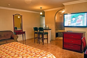 A hotel room with a bed, a desk with chairs, a television, a mirror, and a dresser. - Hotel Milan (Panama City)