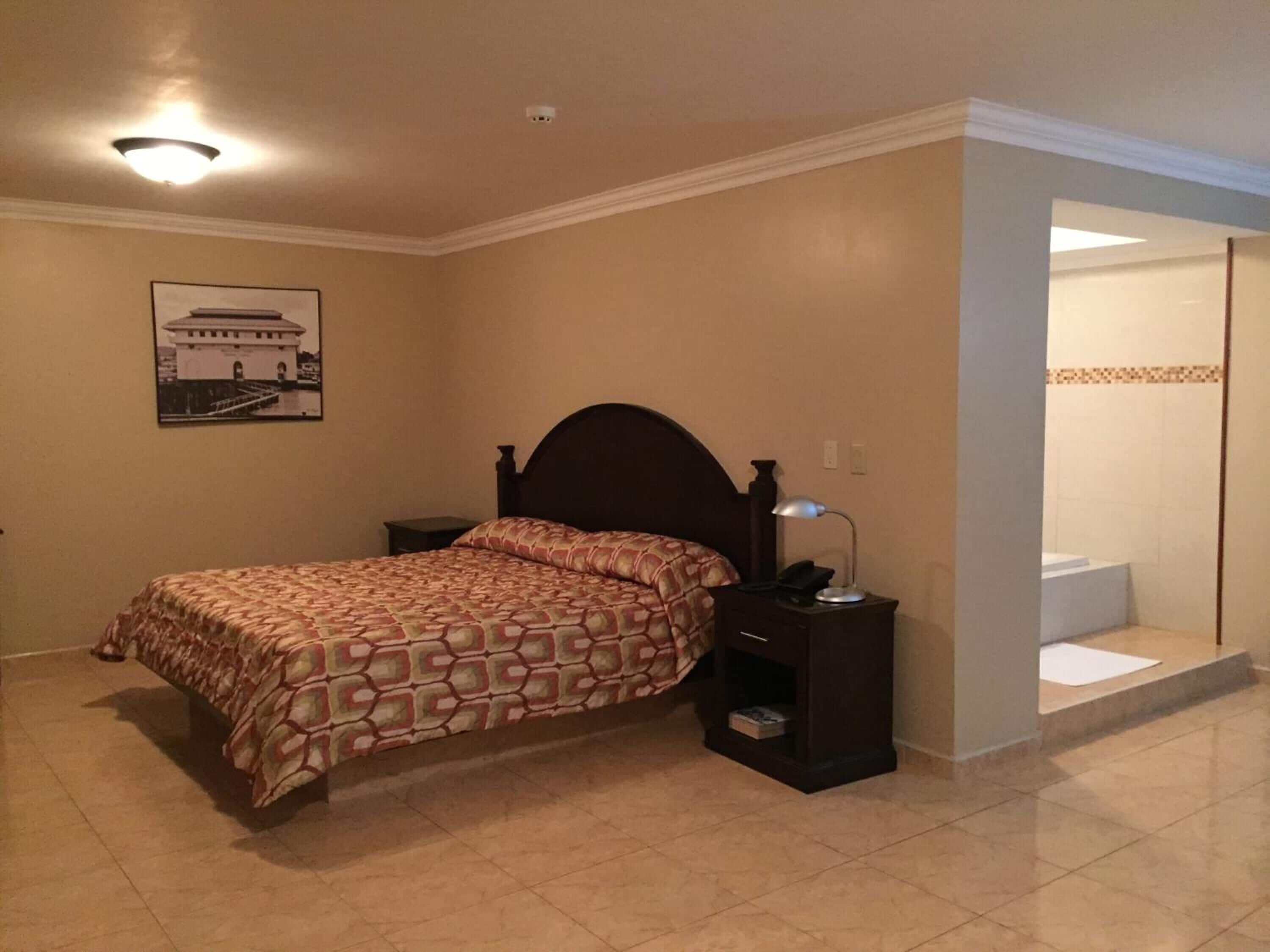 A bedroom with a bed, nightstand, and a picture of a building on the wall.