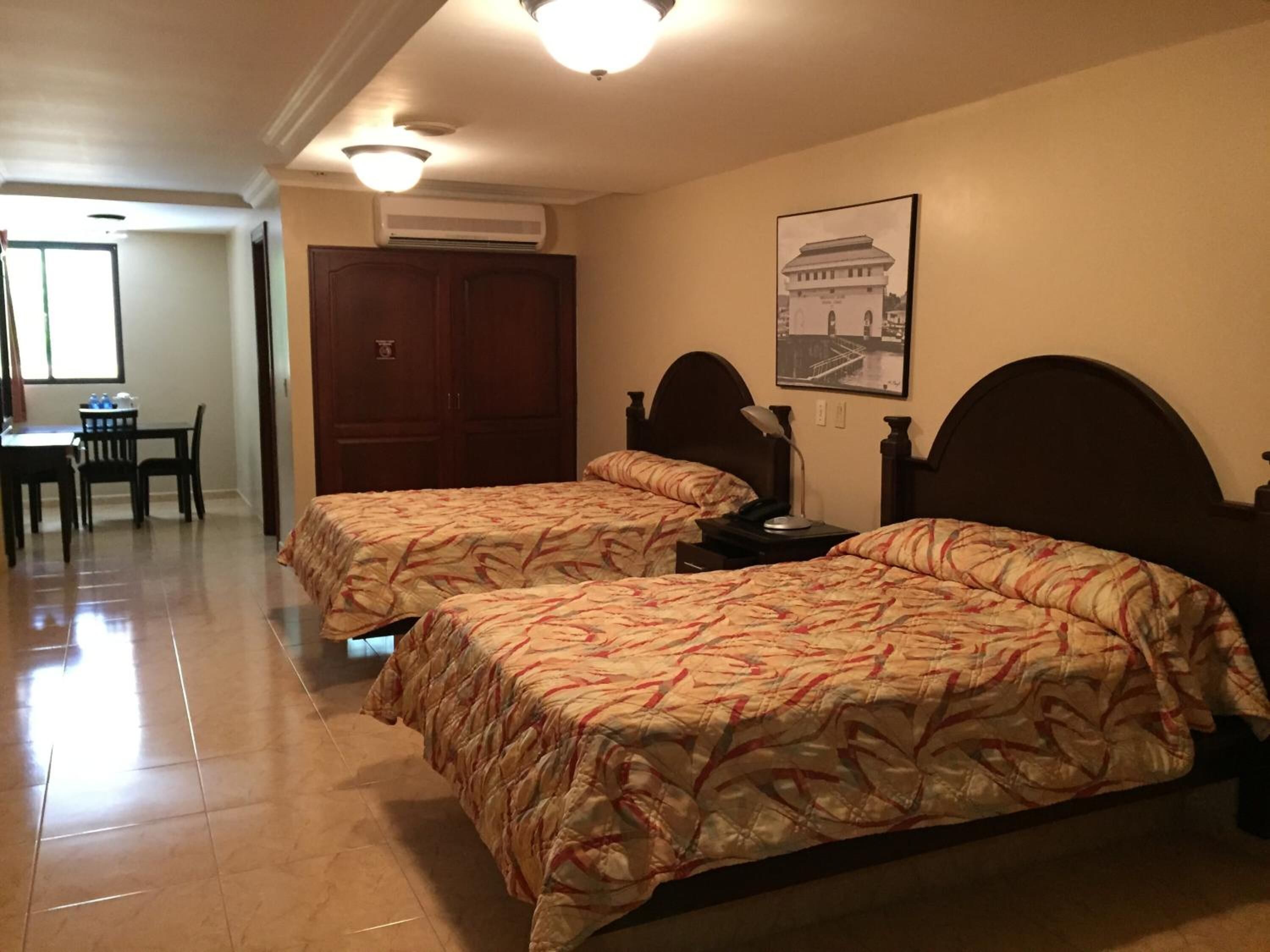 A hotel room with two beds, a desk, and a chair.